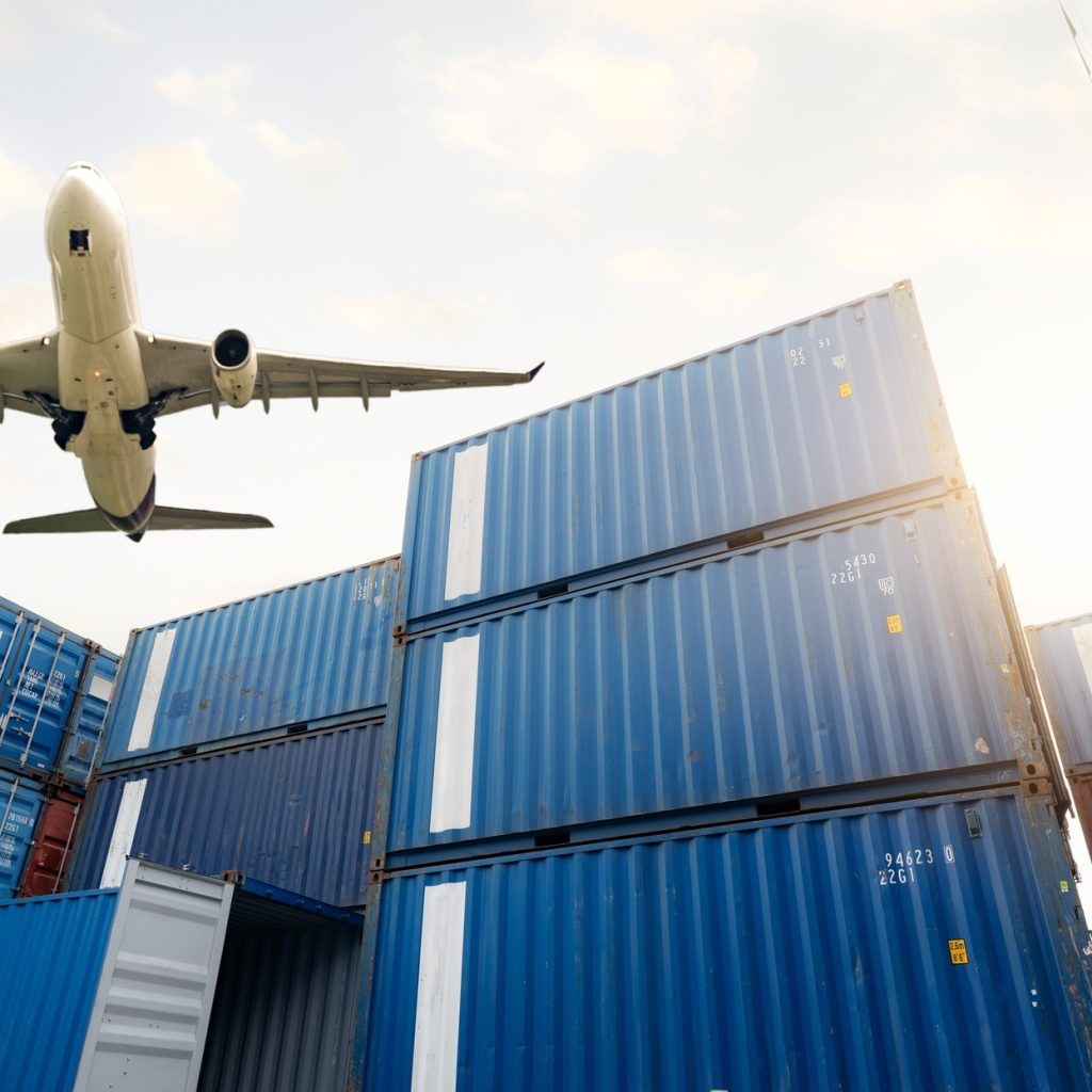 Air logistics. Cargo airplane flying above stack of logistic container. Cargo and shipping business.